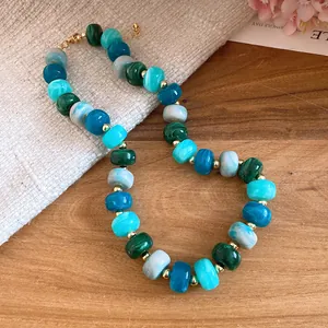 Detailed view of handmade beaded necklace with geometric blue and green marbled beads.