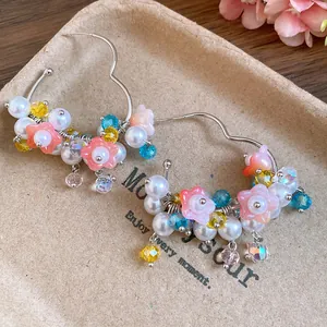 Close-up of elegant floral hoop earrings with pearls and colorful crystals