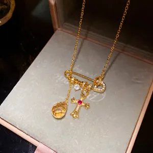 Détail d'un collier épingle de sûreté plaqué or 18k avec croix en zircon et perle