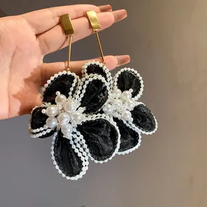 Close-up of elegant mesh flower drop earrings with white pearl accents and gold studs