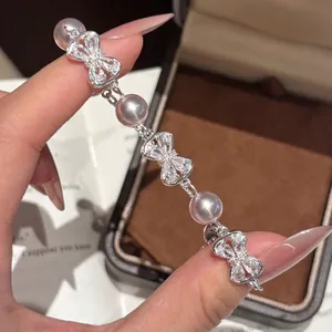 Zoom sur un bracelet élégant en argent avec des perles et des nœuds brillants de luxe.