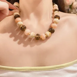 Close-up view of a trendy handmade multi-color geometric beaded necklace worn by a model.