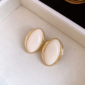 Primer plano de pendientes de resina ovalados vintage con marco de metal dorado brillante