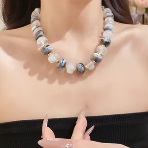 Detailed view of handmade chunky grey and white marbled beaded necklace worn by a model