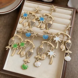 Detailed view of gold ocean-themed drop earrings with fish and palm tree pendants.
