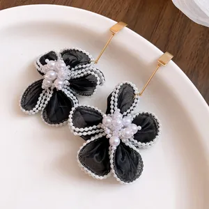 Detailed macro shot of vintage black gauze flower earrings featuring lustrous pearl centers