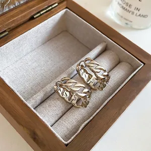 Eleganti orecchini a cerchio a maglie dorate presentati in un portagioie di legno raffinato