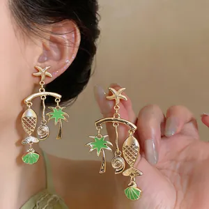Detailed close-up of vintage gold nautical earrings with green enamel fish and palm tree pendants