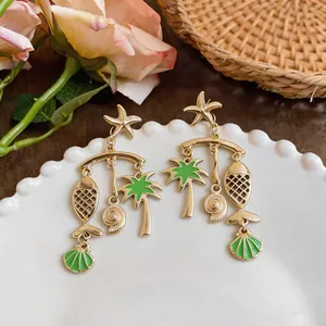Macro view of exquisite gold tropical beach themed earrings with green enamel charms.