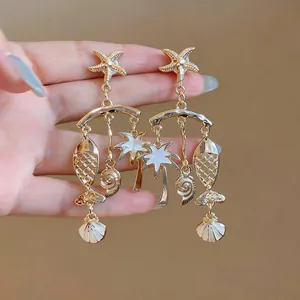 Detail shot of gold-toned tropical dangle earrings with fish and palm tree charms