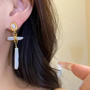 Close-up detail of vintage freshwater pearl cross pendant earrings worn on model's ear