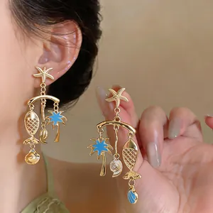 Detailed view of vintage gold dangle earrings with blue enamel fish and ocean charms.