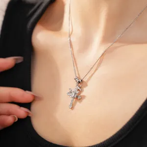 Detailed view of silver star and double cross necklace with zircon stones worn on neck