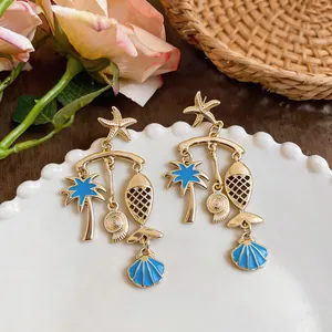 Detail view of blue enamel ocean-themed drop earrings with starfish and fish pendants