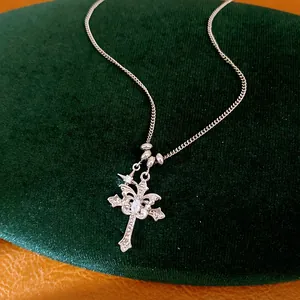 Close-up of silver-tone necklace with zircon-encrusted double cross and star pendant