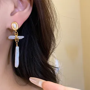 Close-up of vintage gold earrings with freshwater pearl cross pendant shown on model
