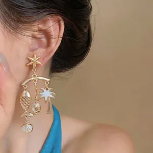 Detailed view of gold ocean-themed drop earrings with enamel fish and shell charms