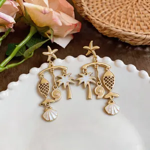 Detail shot of tropical drop earrings with starfish, palm tree, and fish charms on a plate
