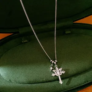 Close-up of silver-tone cross pendant necklace with zircon star on green velvet