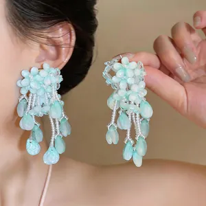 Exquisite close-up of mint green flower tassel earrings with delicate hanging drop details