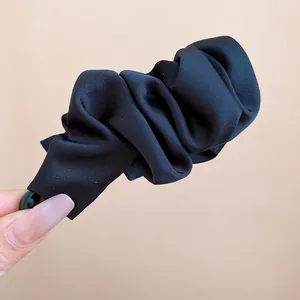 Close-up detail of a minimalist black pleated fabric banana hair clip for high ponytail styling