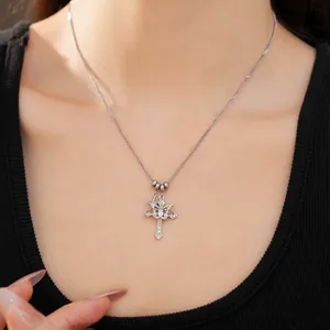 Close-up of a silver double cross necklace with a zircon starburst pendant on a model.