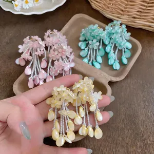 Detailed view of colorful flower tassel earrings in pink, cyan, and yellow colors.
