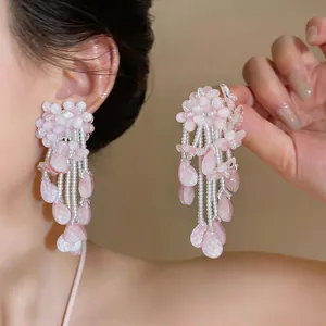 Close-up view of elegant pink flower tassel earrings worn by a model for fashion style