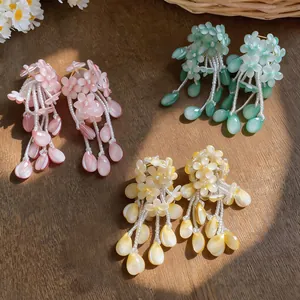 Detailed shot of three colorful floral tassel earrings on a natural wooden background