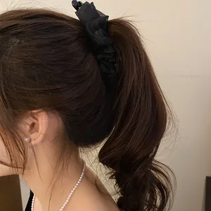 Close-up of black ruffle banana clip holding a high ponytail for elegant hair styling