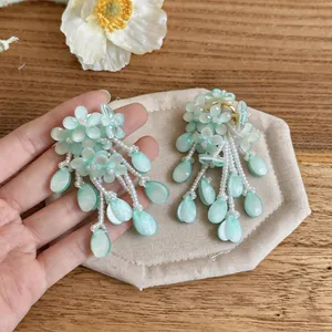 Detailed view of mint green floral tassel earrings with pearlescent teardrop beads
