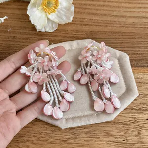 Detail view of pink petal flower tassel earrings with white seed bead dangles on fabric