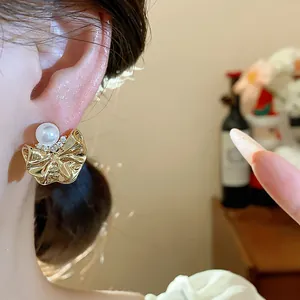 Primo piano di orecchini a fiore dorato plissettato con perla e zirconi