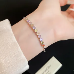 Détail d'un bracelet argenté avec des zircons ronds multicolores et vibrants.