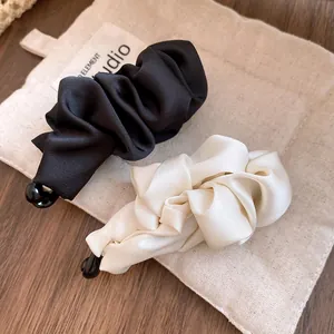Close-up of elegant black and cream ruffled fabric banana hair clips for high ponytails.