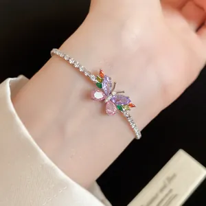 Gros plan d'un délicat bracelet papillon avec des zircons colorés porté au poignet.