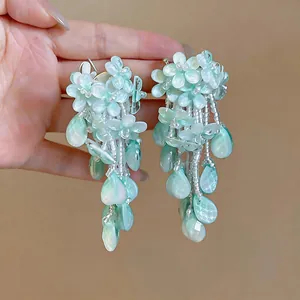 Detailed macro view of mint green floral tassel earrings with pearlized teardrop beads