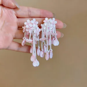 Macro view of unique pink flower tassel earrings with white beads and petal drops.
