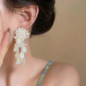 Detailed close-up of elegant mother-of-pearl flower tassel earrings worn by a model