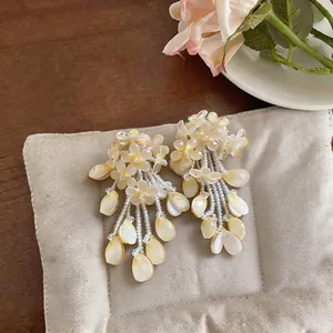 Detail of elegant floral tassel earrings with cream flower petals and dangling beads