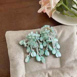 Close-up of mint green floral tassel earrings with pearlescent teardrop charms