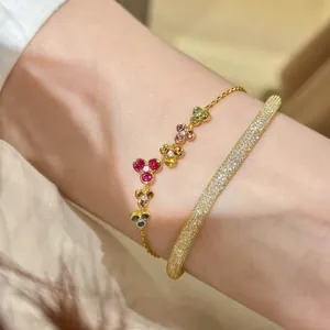 Macro close-up of a colorful gemstone flower bracelet and a gold pavé bangle on a wrist