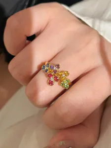 Exquisite gold ring featuring vibrant colorful gemstone flower clusters on a finger