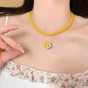 Detailed view of the double-layer necklace with yellow beads and silver flower pendant