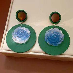 Detailed view of vintage resin earrings featuring a blue rose center on a green round base