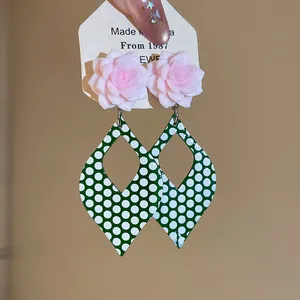 Close-up of vintage green white polka dot flower drop earrings with pink resin studs