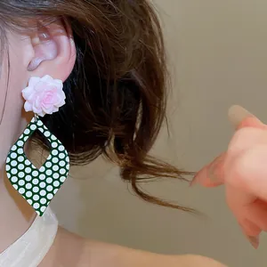 Close-up of retro green and white polka dot flower earrings worn for a stylish look