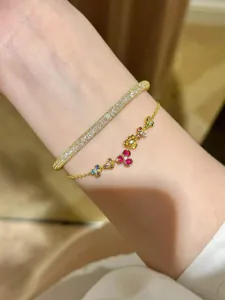 Detailed view of colorful gemstone flower bracelet paired with gold pavé bangle