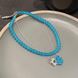 Detailed macro view of blue frosted glass bead double-layer necklace with flower charm