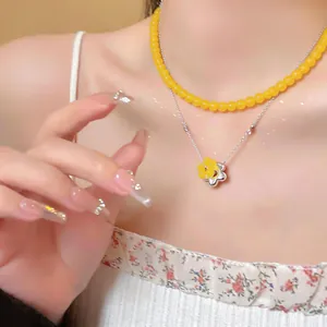 Close-up of double-layer French style necklace with yellow glass beads and flower pendant